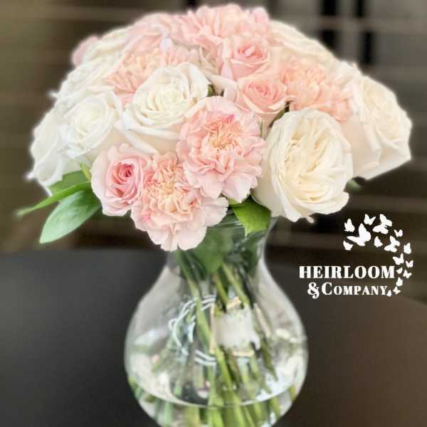 Pink and white roses with carnations in a clear glass vase