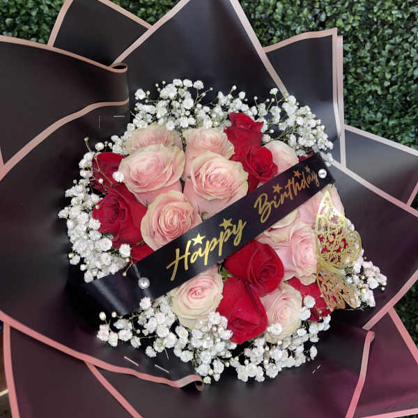 Bouquet of pink and red roses with baby's breath and a birthday ribbon