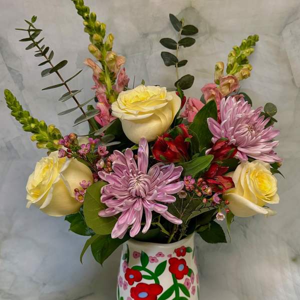 Bouquet of yellow roses, pink chrysanthemums, and red alstroemeria in a painted vase