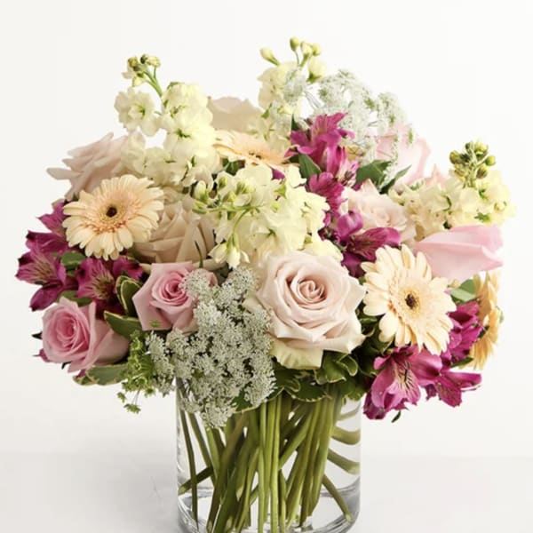 Mixed pink and cream flowers arranged in a clear glass vase