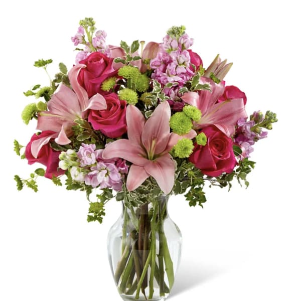Pink roses and lilies arranged in a clear glass vase