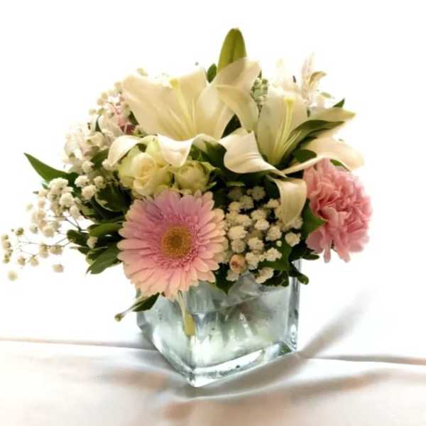 Pink and white flower arrangement in a square glass vase