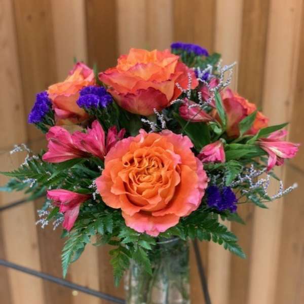 Orange and pink rose bouquet in a clear glass vase