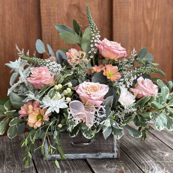 Pink roses and peach daisies arranged in a rustic wooden box
