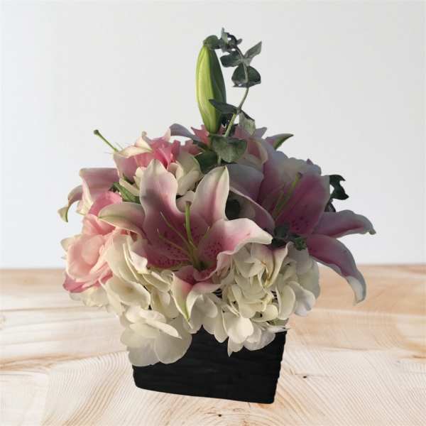 Pink lilies and white hydrangeas in a black container