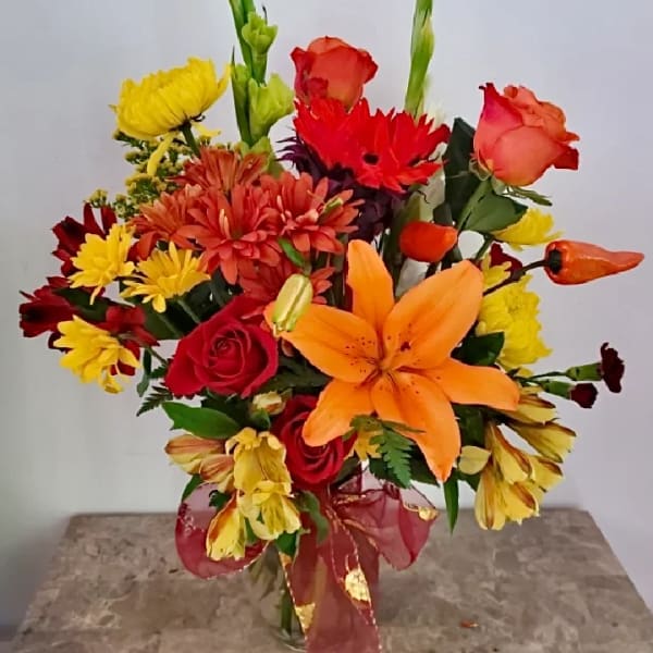 Colorful mixed bouquet with roses, lilies, and daisies in a glass vase
