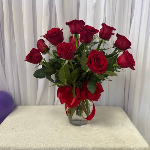 Red roses in a clear glass vase with a red ribbon