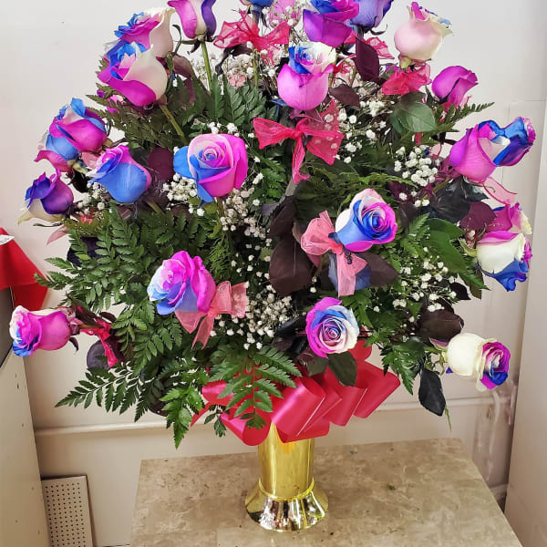Bouquet of multicolored roses in a gold vase with pink ribbon