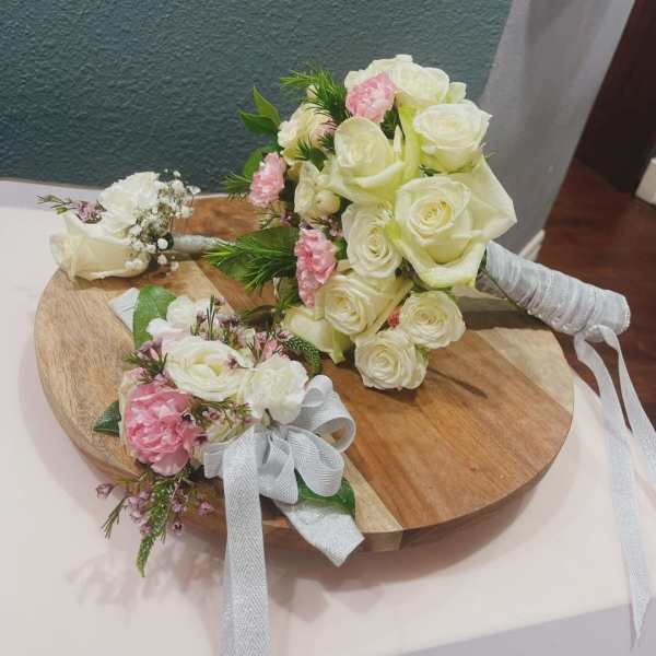 White and pink rose bouquets with ribbon on a wooden board