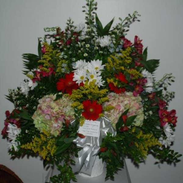 Large standing floral spray with mixed red, white, pink, and yellow flowers