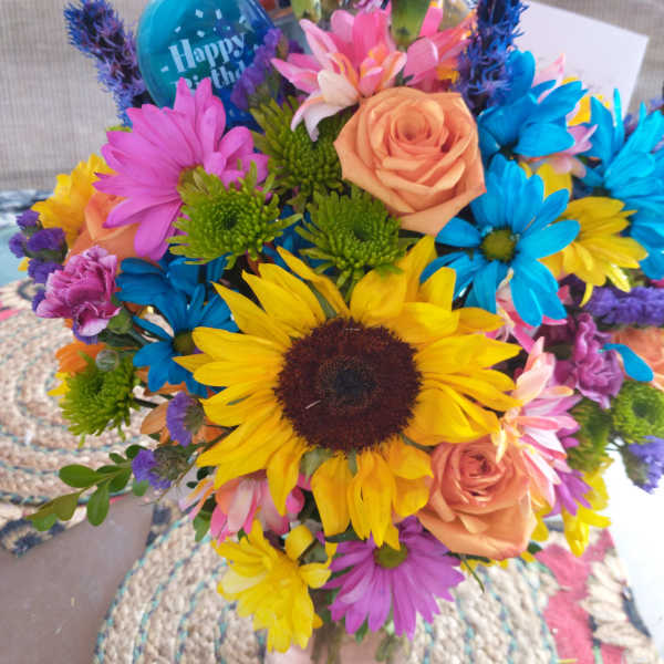 Colorful bouquet with sunflowers, roses, and daisies in a vase