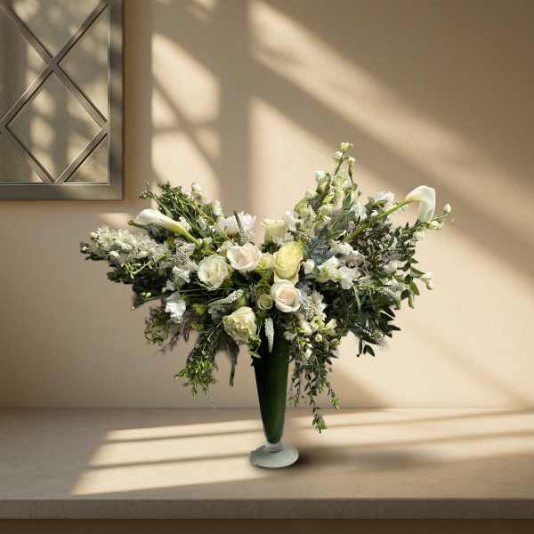 Large white floral arrangement in a tall green vase