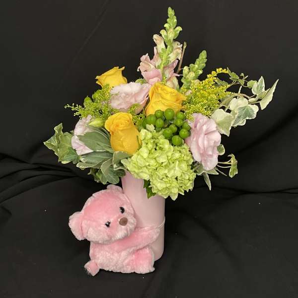 Pink teddy bear with a pastel flower arrangement in a pink vase