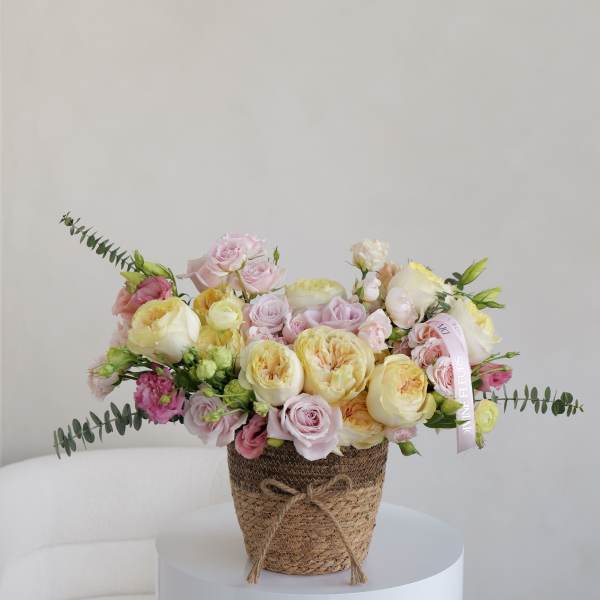Pastel rose bouquet in a woven basket with ribbon
