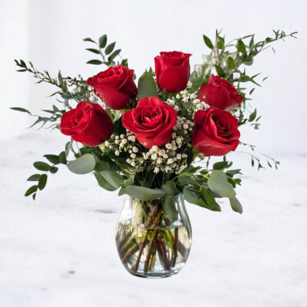 Arrangement of red roses with white filler flowers in a clear glass vase