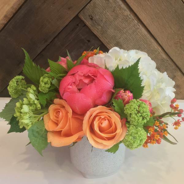 Mixed bouquet of pink, orange, and white flowers in a white vase