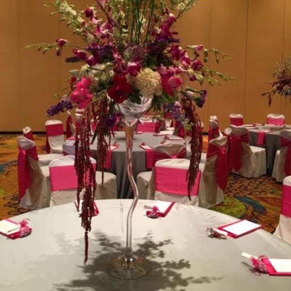 Tall floral centerpiece in a glass vase on a banquet table