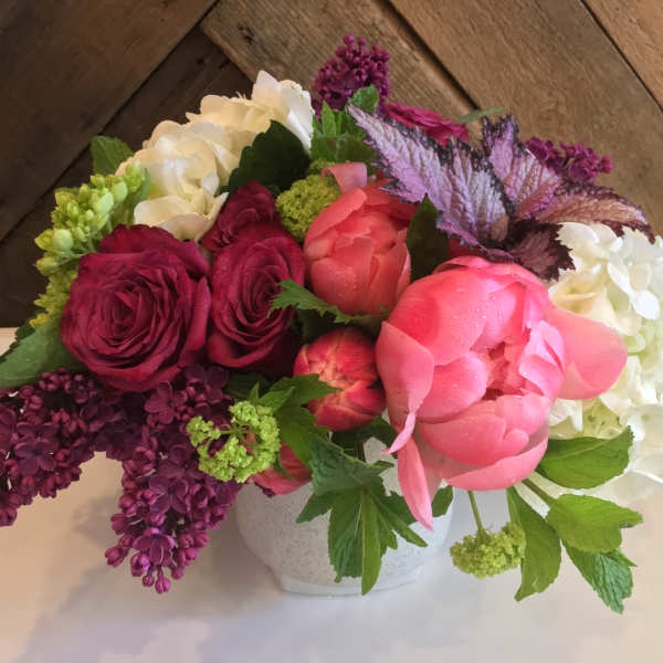 Pink and burgundy roses with white hydrangeas in a white vase