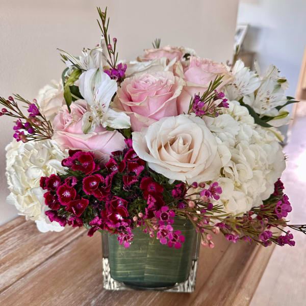 Pink and white roses arranged in a square glass vase