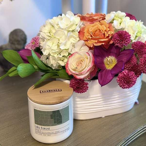 Mixed bouquet in a white container with roses, hydrangeas, and purple blooms