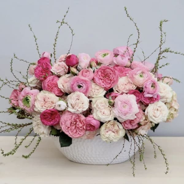 Pink and white ranunculus arrangement in a white bowl vase