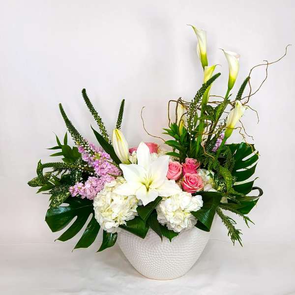 White lilies, pink roses, and hydrangeas in a white vase