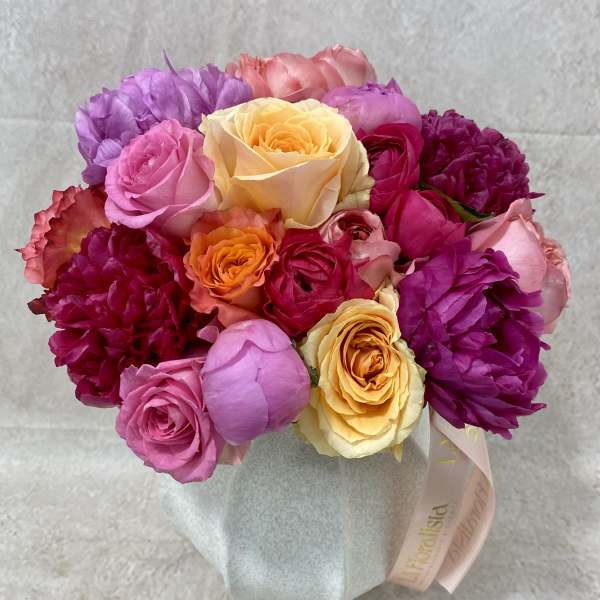 Mixed bouquet of pink, purple, and yellow roses in a wrapped base