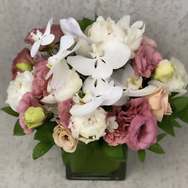 Bouquet of white orchids and pink mixed flowers in a square glass vase