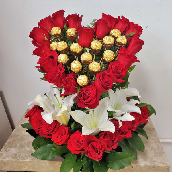 Heart-shaped bouquet of red roses with white lilies and gold-wrapped chocolates