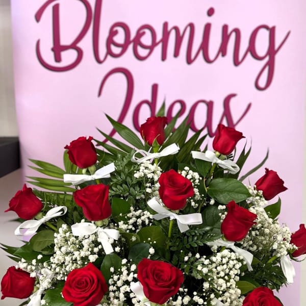 Bouquet of red roses with baby's breath and white ribbons in a white vase