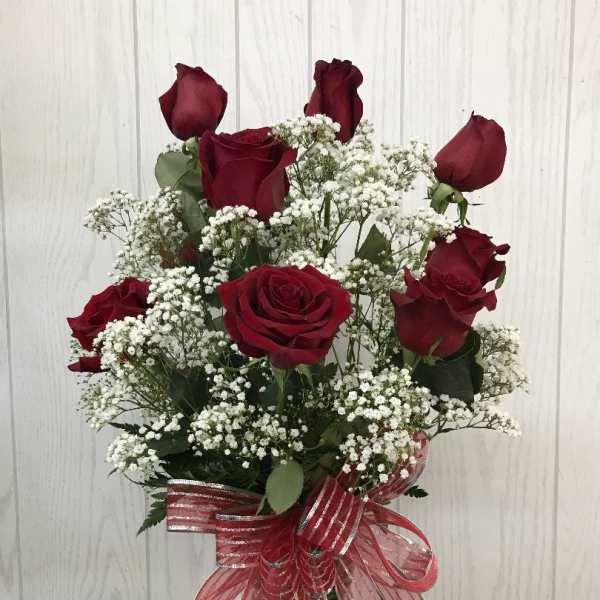 Bouquet of red roses and baby's breath in a glass vase with a red ribbon