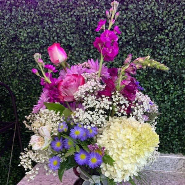 Mixed bouquet in a dark glass vase with pink, purple, and white flowers