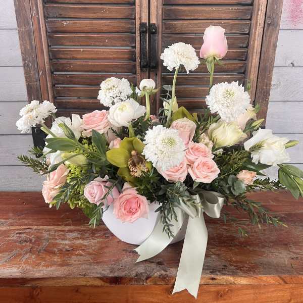 Pink and white floral arrangement in a white box with a ribbon