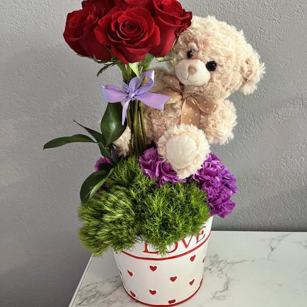 Red roses with a teddy bear in a heart-decorated pot