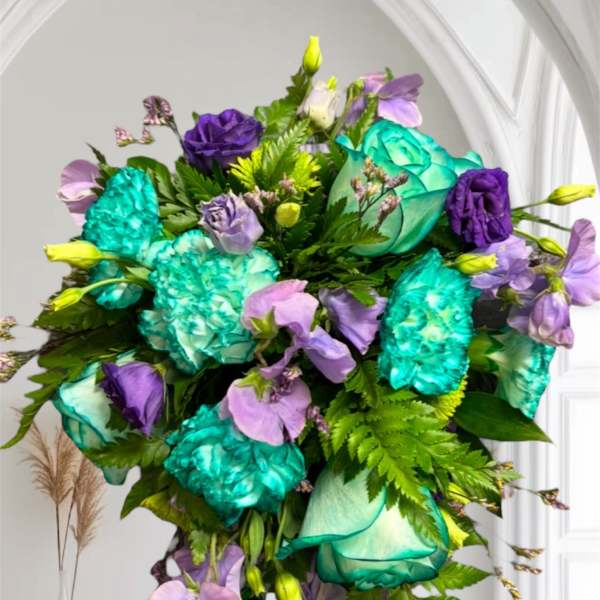 Bouquet of teal, purple, and lavender flowers with greenery