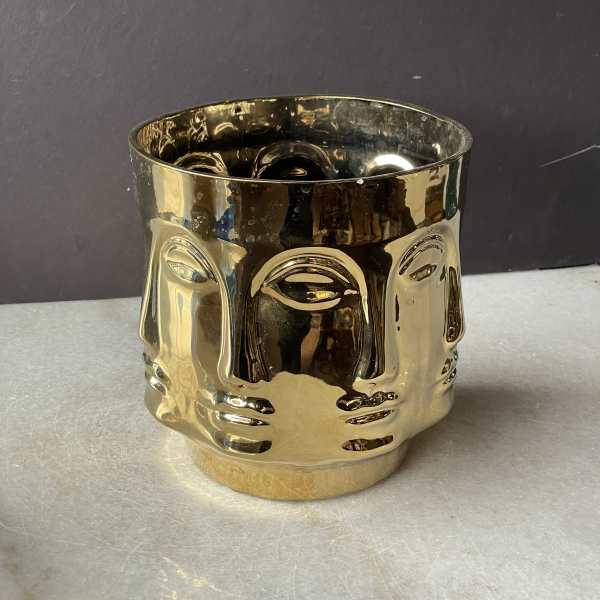 Gold metallic decorative candle holder with a face design
