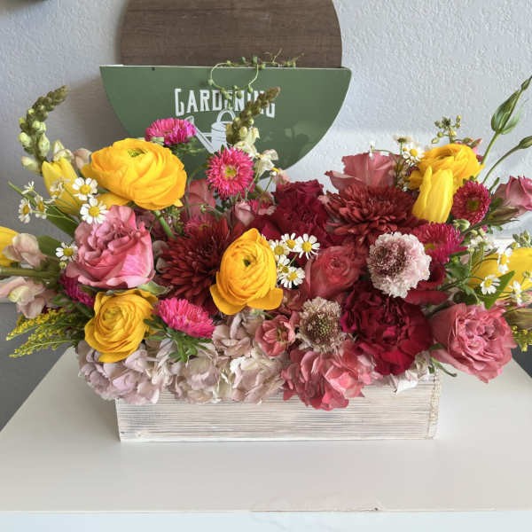 Colorful mixed flower arrangement in a white wooden box