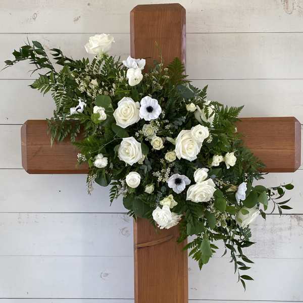 White floral spray arranged on a wooden cross