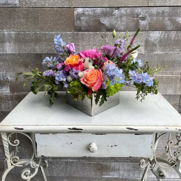 Colorful mixed flower arrangement in a square metal container