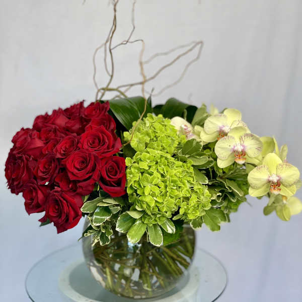 Red roses and green hydrangeas in a glass vase with pale orchids