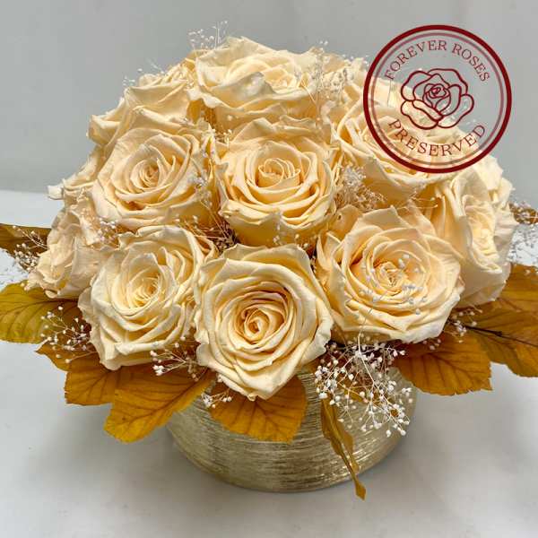 Cream roses arranged in a round gold box with dried filler and autumn leaves