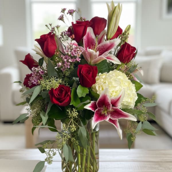 Red roses and pink lilies arranged in a clear glass vase