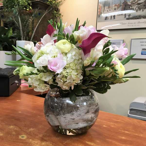 Mixed bouquet of white, pink, and purple flowers in a glass vase