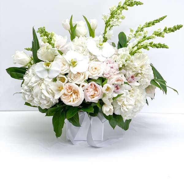 White floral arrangement in a square box with pale pink roses