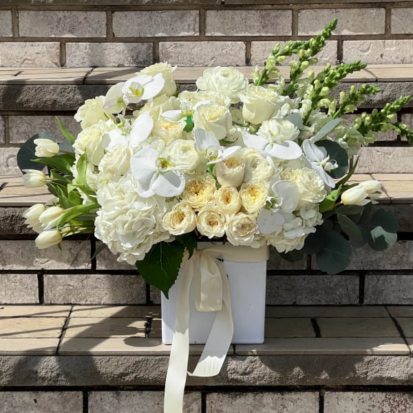 White floral arrangement in a square box with a ribbon