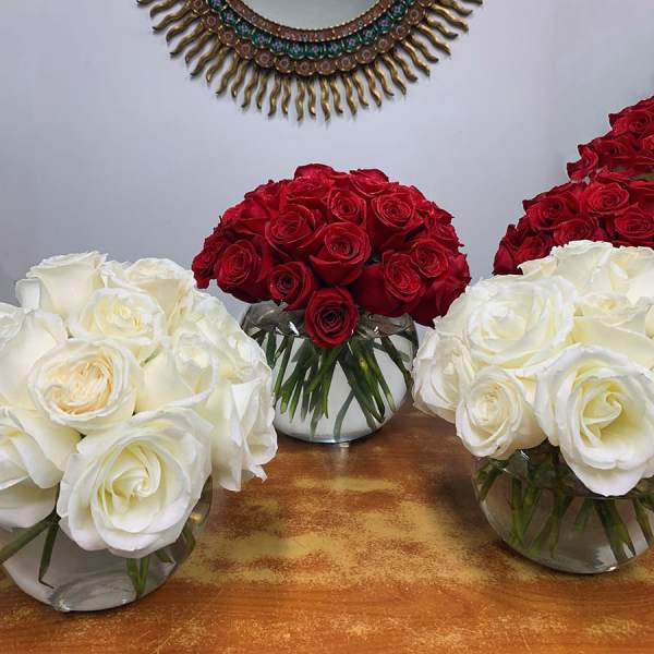 Three rose arrangements in clear glass bowls, in red and white.
