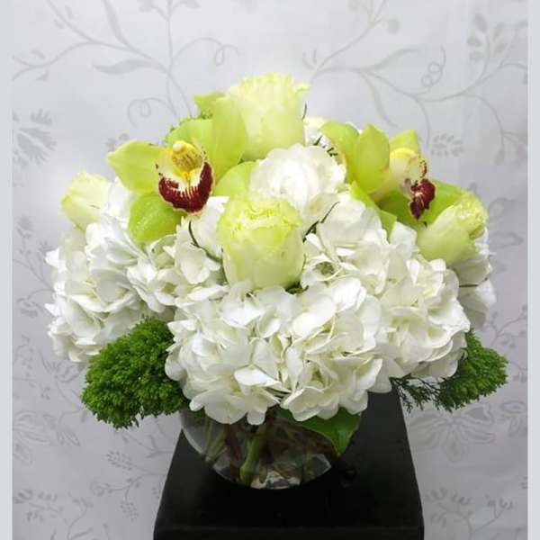 White hydrangea and green orchid bouquet in a glass vase