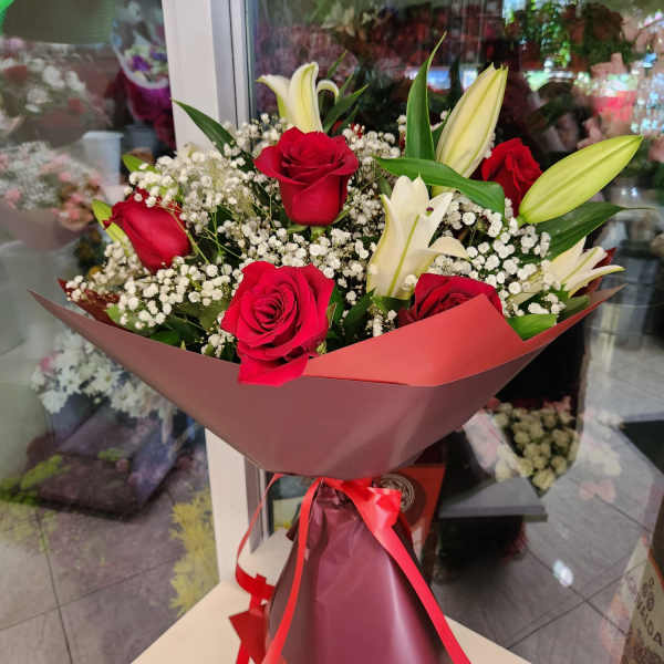 Bouquet of red roses and white lilies wrapped in pink paper