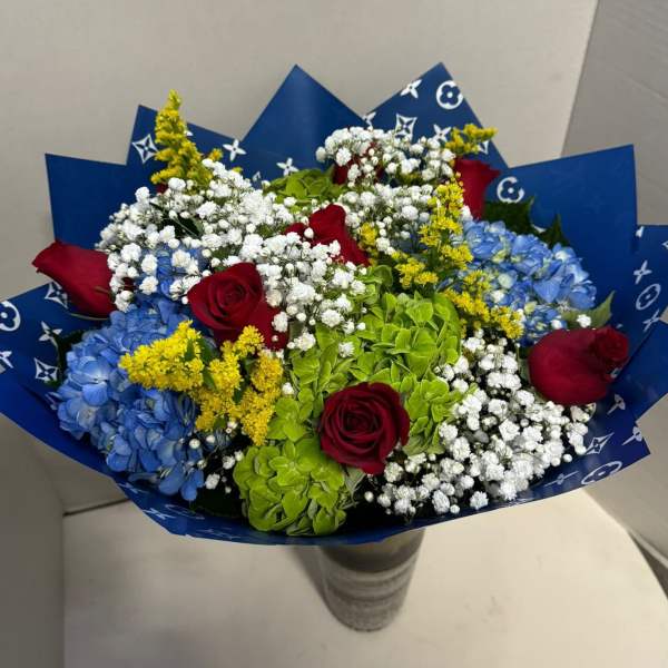 Bouquet of red roses, blue hydrangeas, and white baby's breath in blue wrap