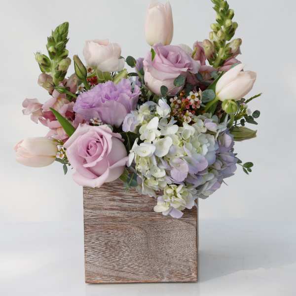 Pastel bouquet of roses, tulips, hydrangea, and snapdragons in a wooden box